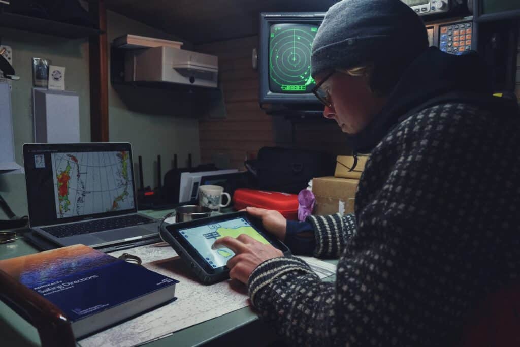 Navigator of the Northwest Passage expedition checking weather parameters and direction on a SailProof tablet.