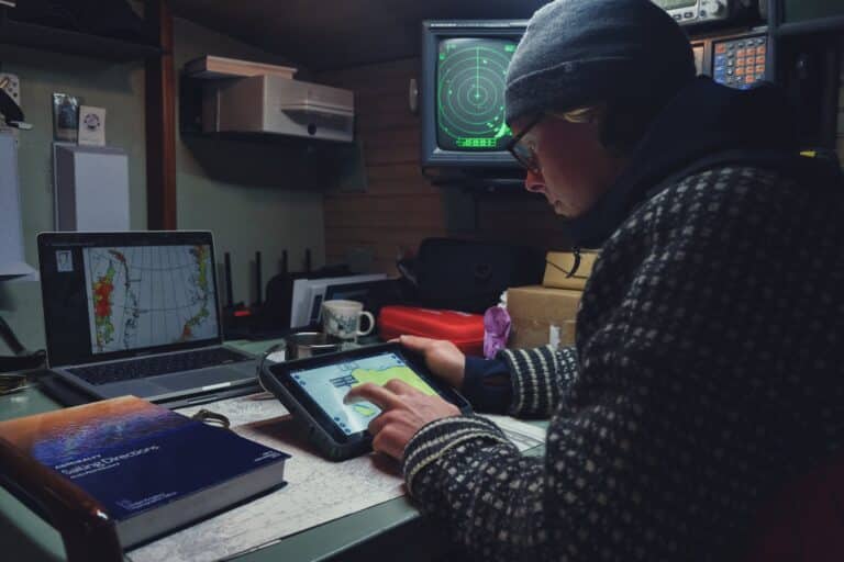 Navigator of the Northwest Passage expedition checking weather parameters and direction on a SailProof tablet.