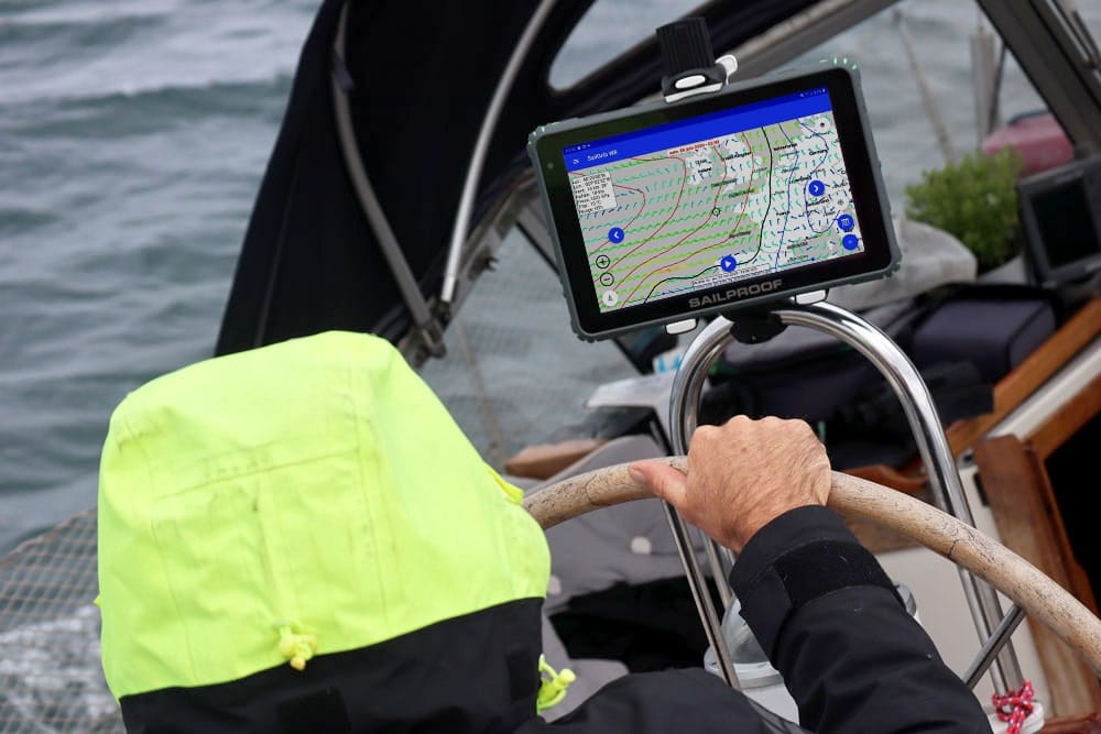 Tablet marino robusto SailProof SP10X con l’app SailGrib WR in funzione nella cabina di comando durante una navigazione.

