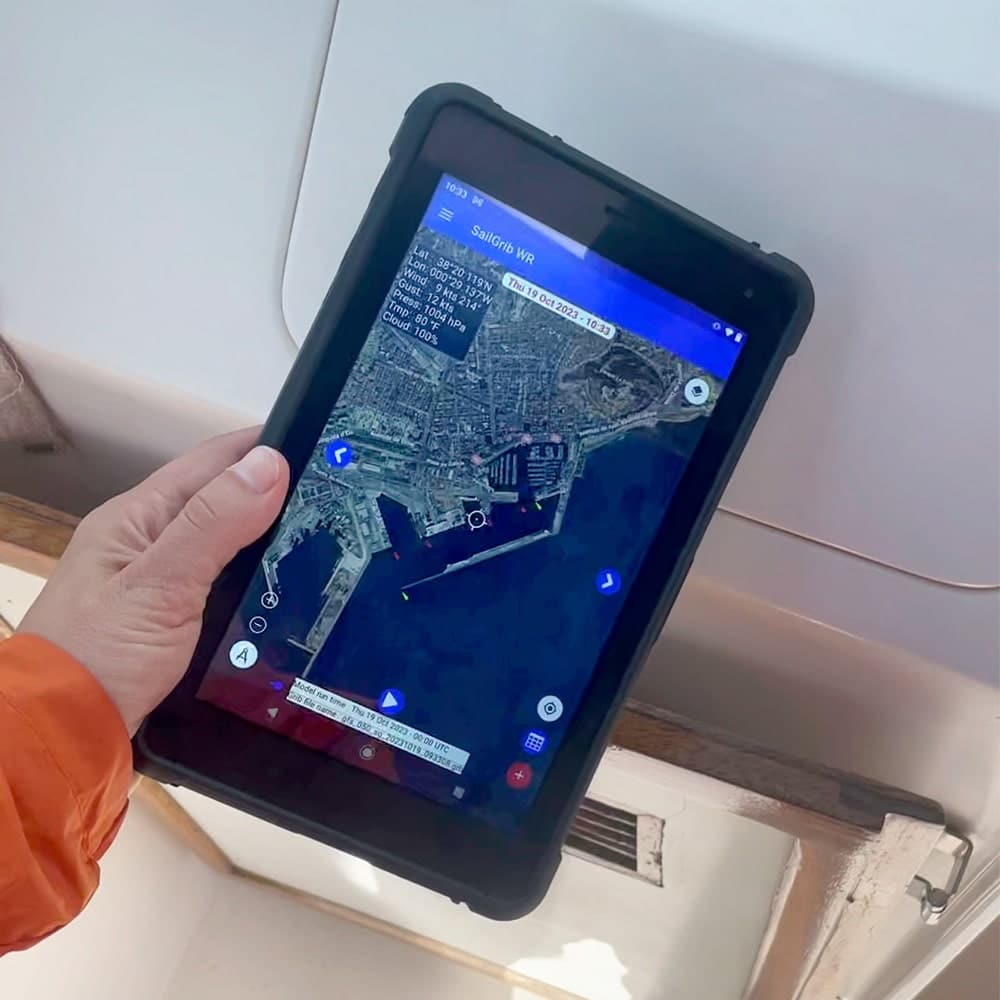 Tablet robusto SailProof SP08 con l’app SailGrib in funzione, tenuto da un velista durante una manovra.
