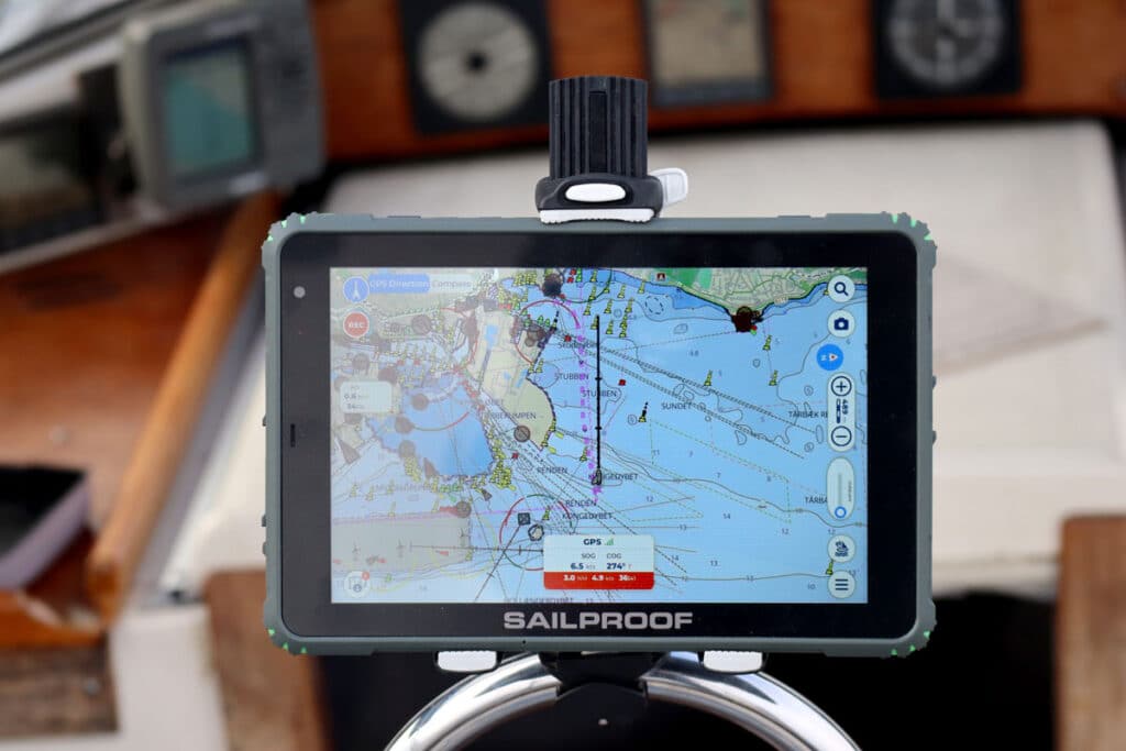SailProof tablet running Aqua Map navigation mounted at the helm of a sailboat while sailing through Danish waters, providing reliable navigation in outdoor marine conditions.